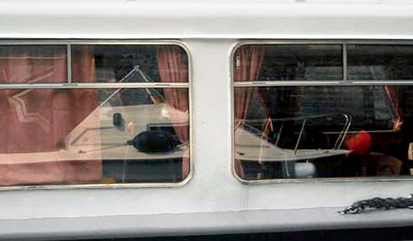 Wilson-neben-Ausflugsdampfer Ob das gut geht? Ganz kleines Boot spiegelt sich im großen Boot.