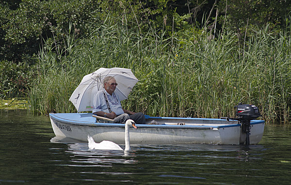 Mann mit Sonnenschirm im Boot